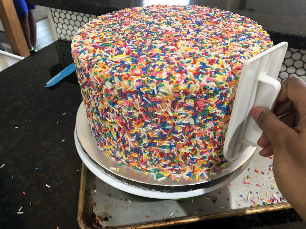 pressing sprinkles on to cake
